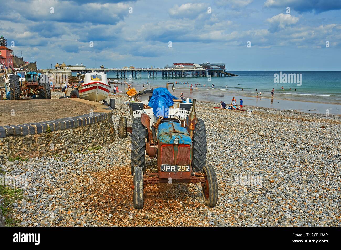 Cromer, Norfolk, Traktoren schleppen Boote den Strand hinauf als eine der wenigen Strandfischerflotten, die in Großbritannien noch übrig sind Stockfoto