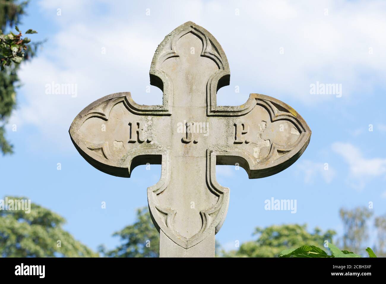 Steinkreuz vor einem bewölkten Himmel auf einem Historischer Friedhof in deutschland Stockfoto