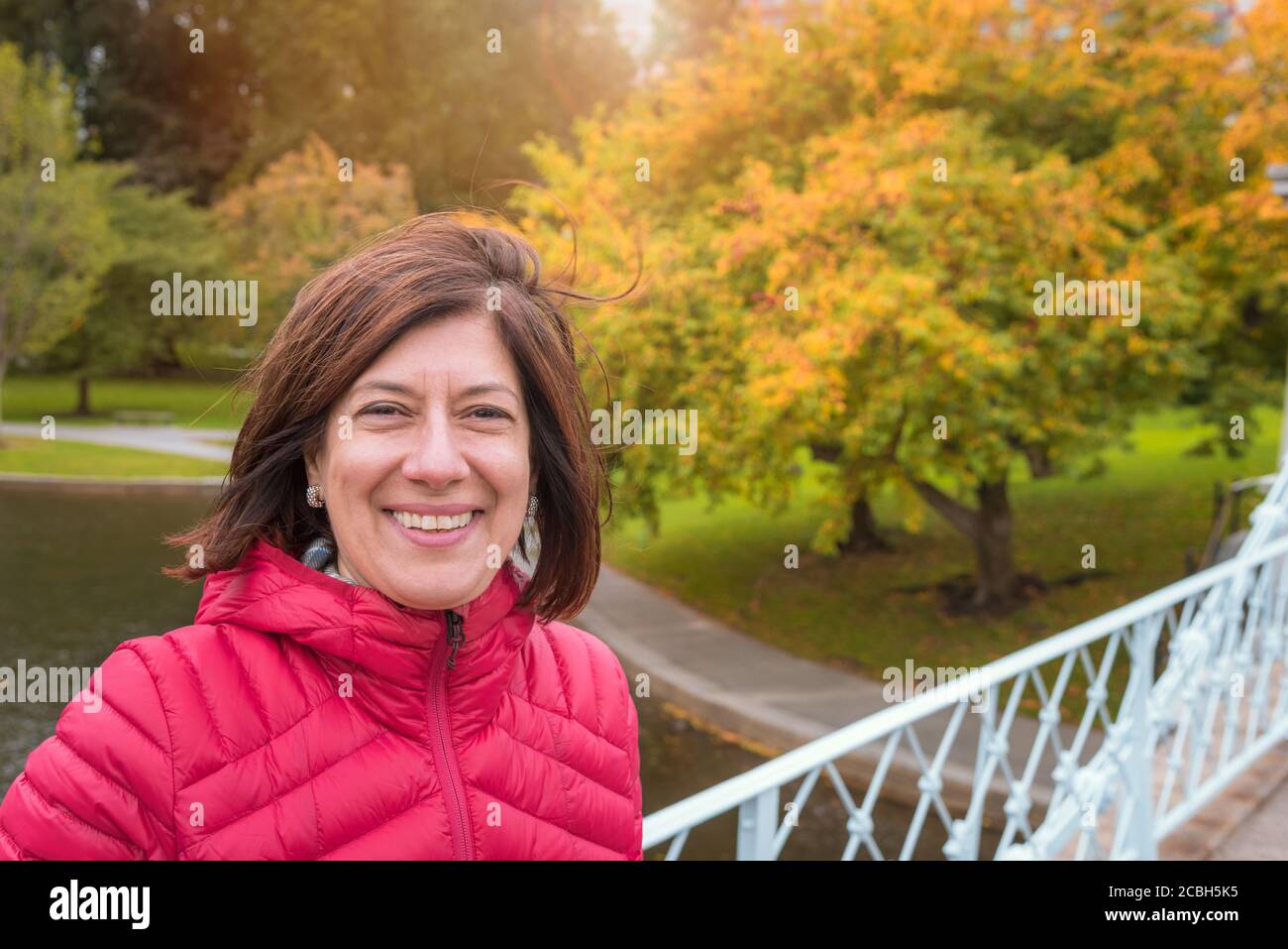 Porträt einer lächelnden Frau in einem Park im Herbst. Herbstfarben im Hintergrund. Konzept der Hapiness. Stockfoto