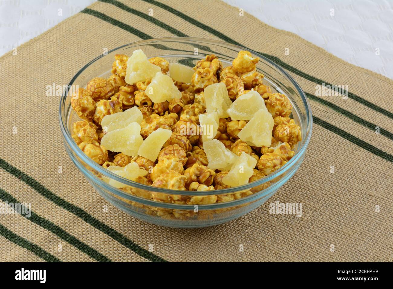 Karamell Popcorn und getrocknete Ananas Chunk Mischung in Glas Snack  Schüssel auf gewebter Platzmatte Stockfotografie - Alamy