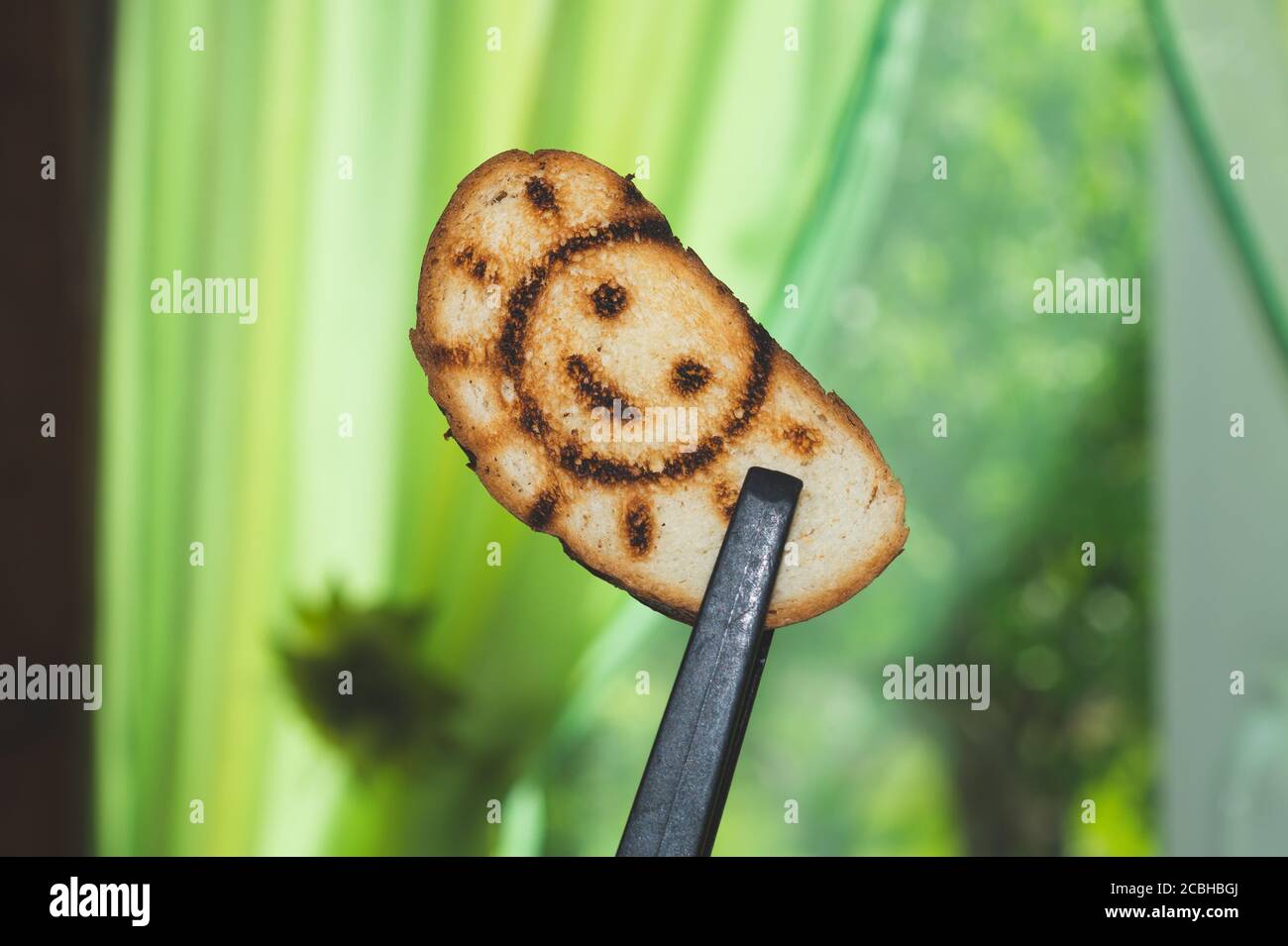 Geröstetes Brot mit lächelndem Sonnenbild. Symbol auf dem Toast Stockfoto