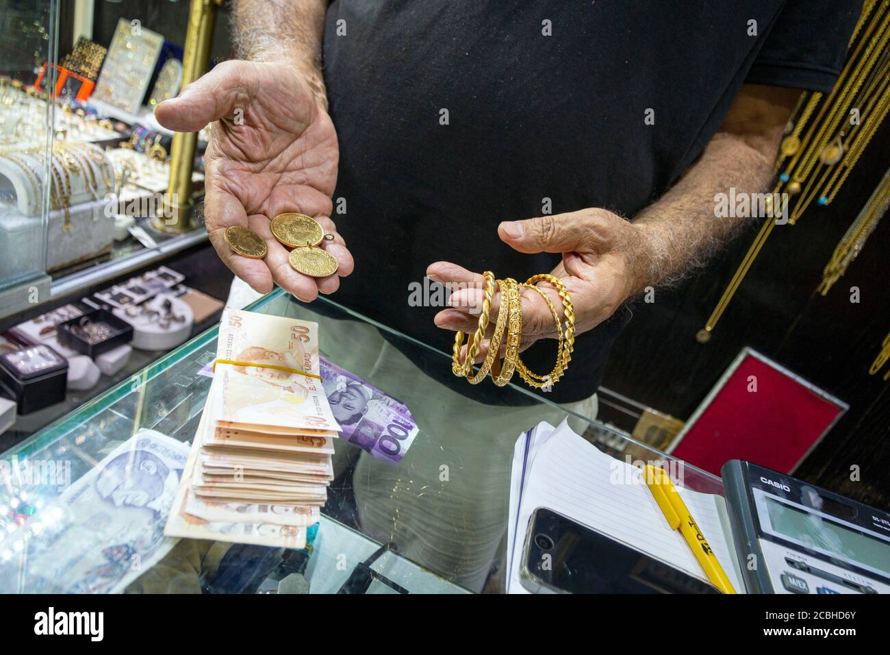 Ankara, Türkei. August 2020. Ein Mann vergleicht am 13. August 2020 in einem Juweliergeschäft in Ankara, Türkei, Gold und abwerdende türkische Lira. Einen Tag nach dem jüngsten Aufruf von Präsident Recep Tayyip Erdogan, die Kreditkosten zu senken, um das Wirtschaftswachstum anzukurbeln, reduzierte die Zentralbank die billigere Liquidität, die sie den Primärhändlern im Rahmen ihrer Offenmarktgeschäfte zur Verfügung stellt, vom 12. August auf Null, so eine Erklärung am Dienstag. (Foto von Tunahan Turhan/INA Photo Agency/Sipa USA) Quelle: SIPA USA/Alamy Live News Stockfoto