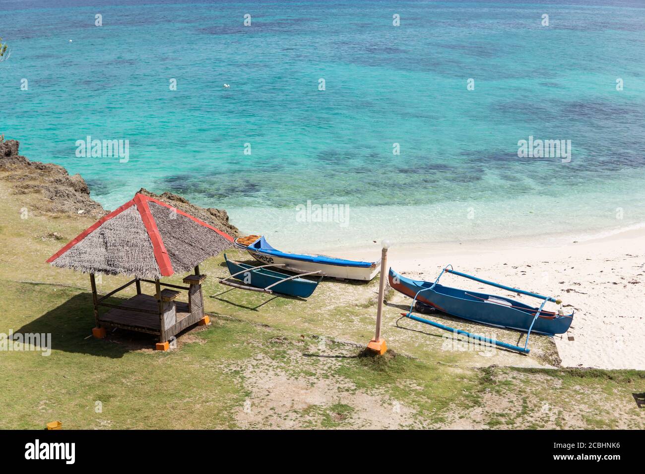 Schöner weißer Sandstrand und türkisfarbenes Wasser mit Holzboot auf dem Sand, Anda Strand, Bohol, Philippinen Stockfoto