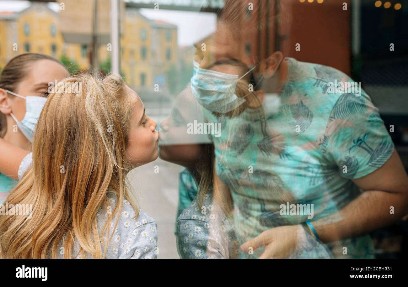 Mädchen geben einen Kuss durch das Glas zu ihrem Vater Stockfoto