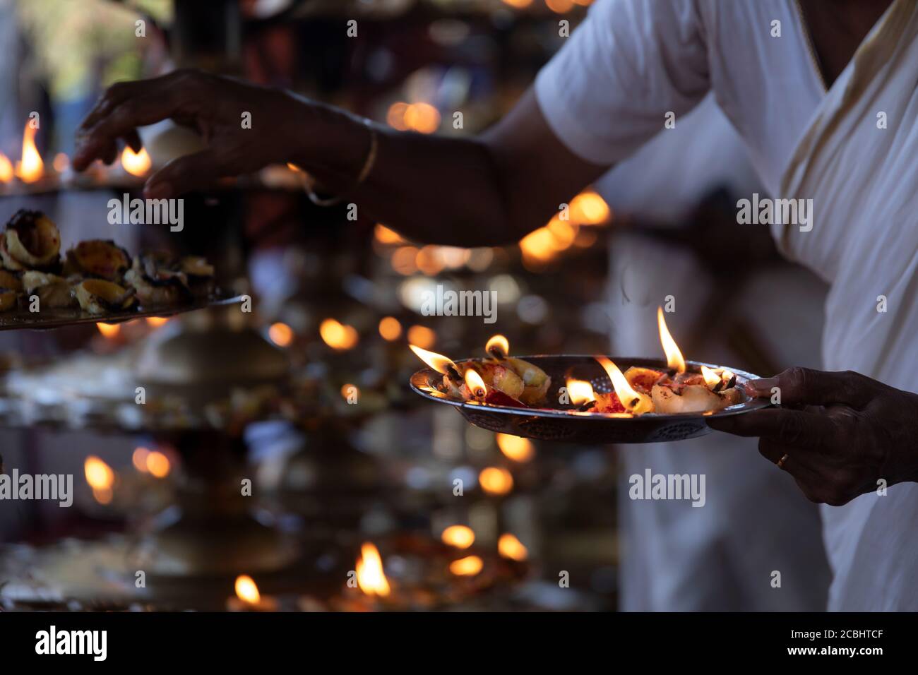 Eifrige Anhänger, die Zitronenlampen als hinduistisches Ritual anzünden Stockfoto