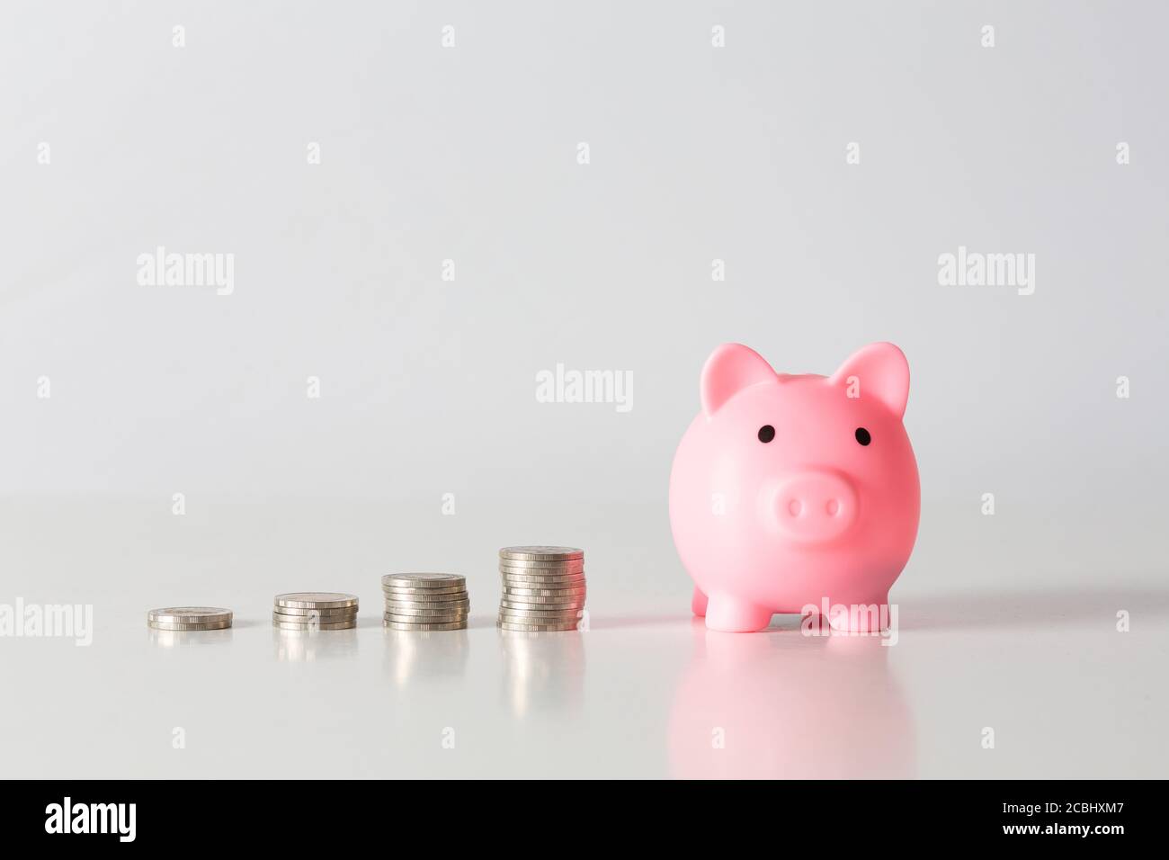 Hand des Kindes hält Münze in Sparschwein mit Geldstapel wachsendes Wachstum Geld sparen, Konzept Invesment für finanzielle Freiheit Plan, Geschäft. Stockfoto