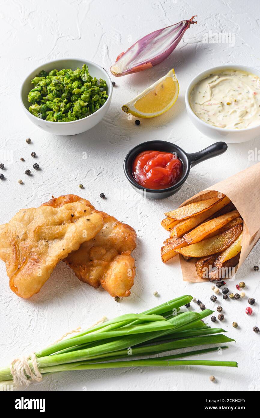 Fish & Chips mit Dip und Zitrone in einem Papier Kegel auf weißem Hintergrund mit allen Komponenten klassische Rezept zum Mitnehmen Food weißen Stein strukturierten Hintergrund Stockfoto