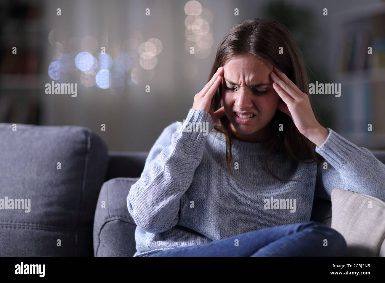 Frau in Schmerzen leiden Migräne-Angriff in der Nacht in der Wohnzimmer zu Hause Stockfoto