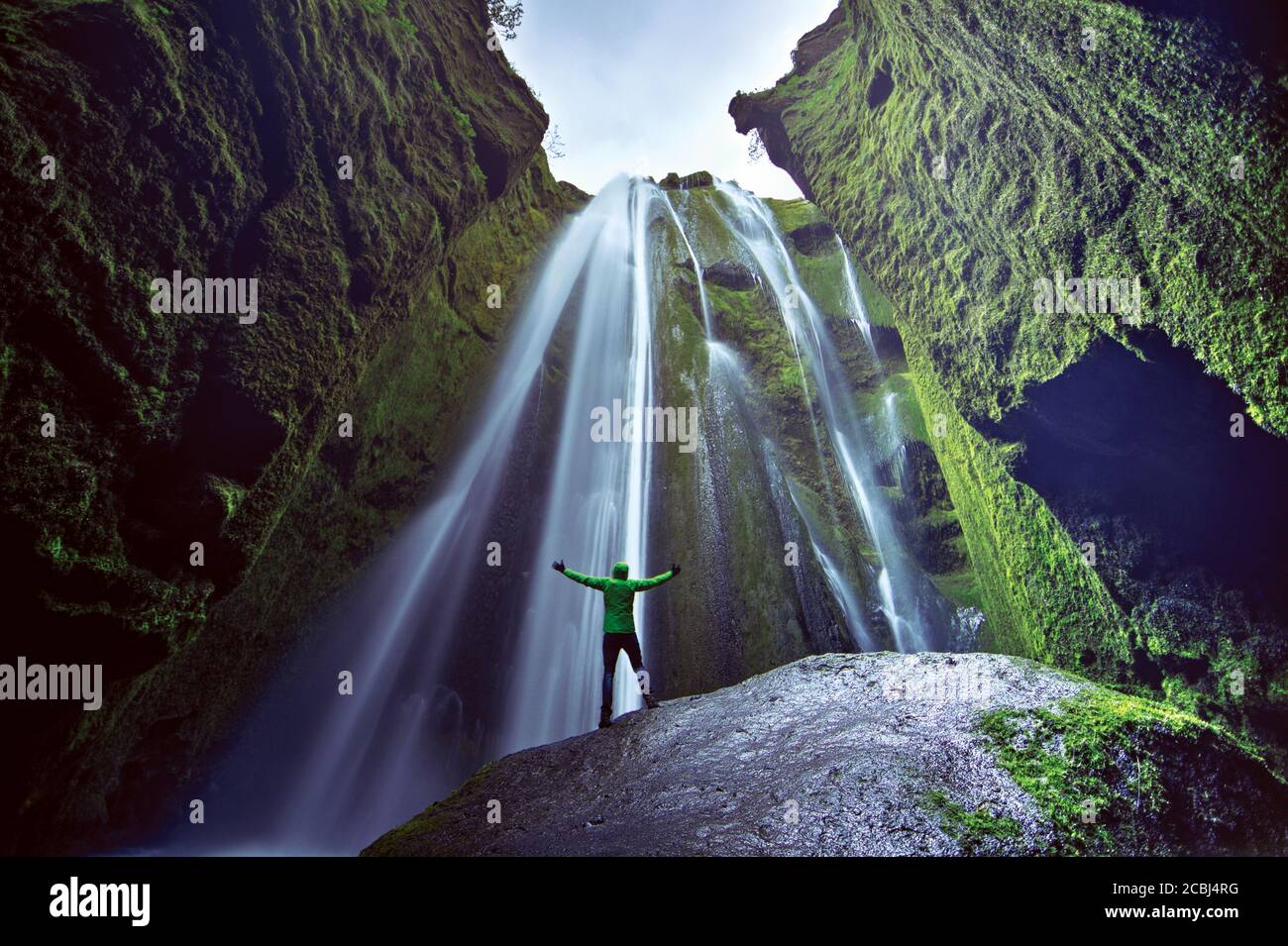 Mann, der mit den Händen in der Luft vor dem Wasserfall Gljufrafoss, Island, steht. Konzept von Stärke und Sieg. Stockfoto