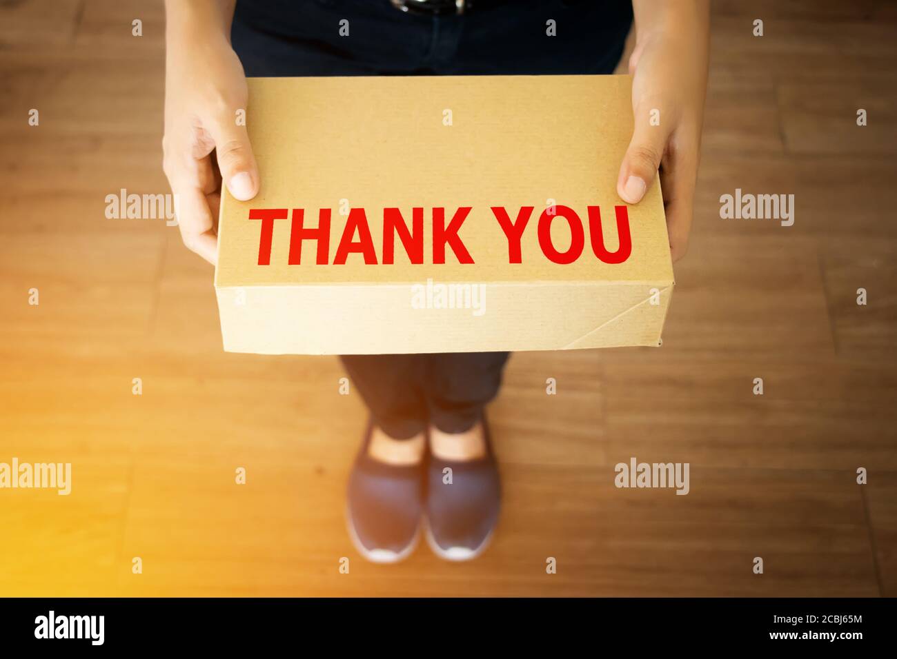 Danksagung für Kunden, die mit Ihrem Shop-Konzept einkaufen : Danksagung Wort auf einfache Lieferung braune Box in der Hand des freundlichen Boten Stockfoto