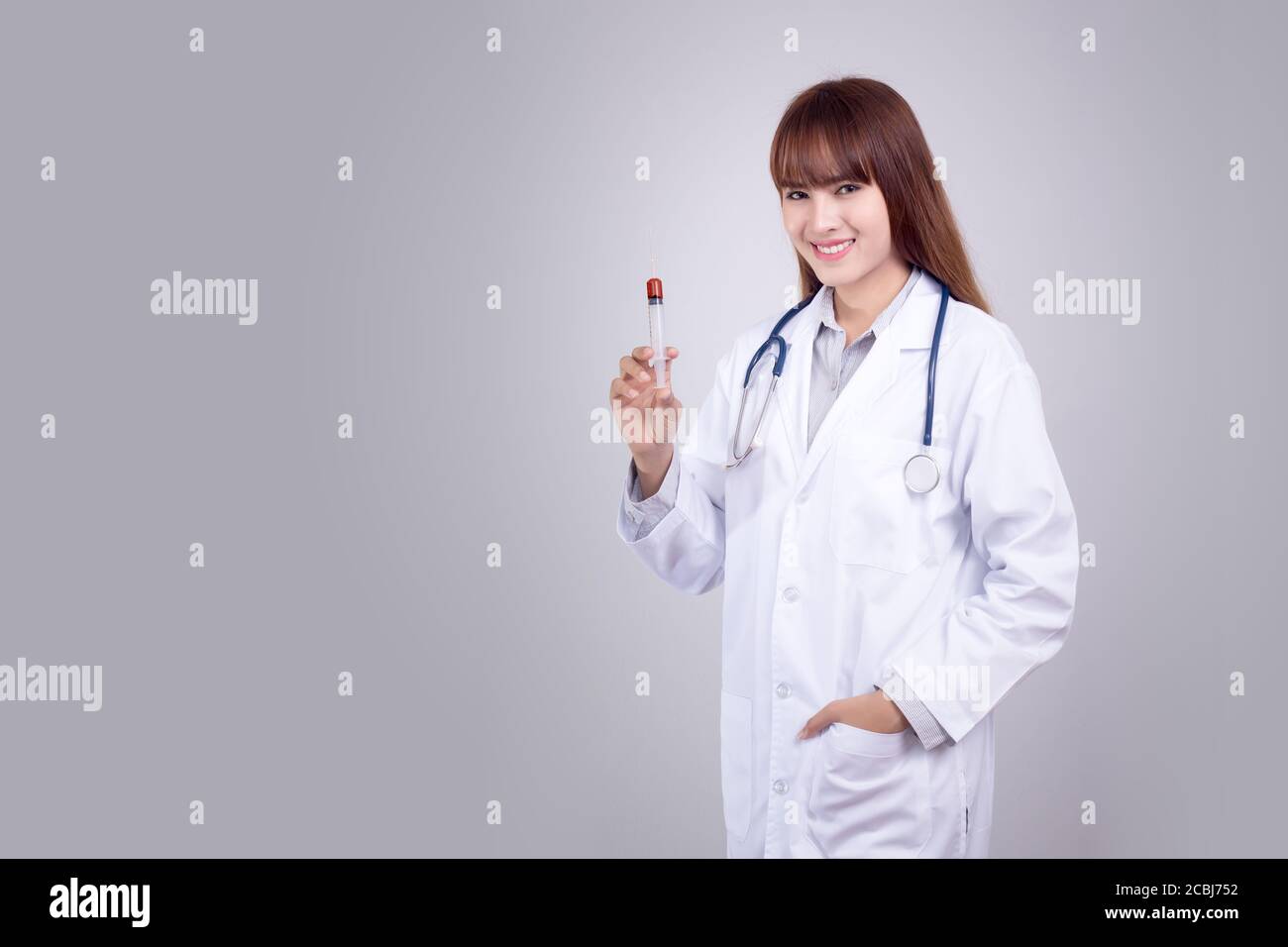 Gesundes Konzept : Junge asiatische Arzt mit hypodermic Spritze in der Hand isolieren auf grauem Hintergrund. Arzt, Klinik, Krankenhaus Poster und Werbung Stockfoto