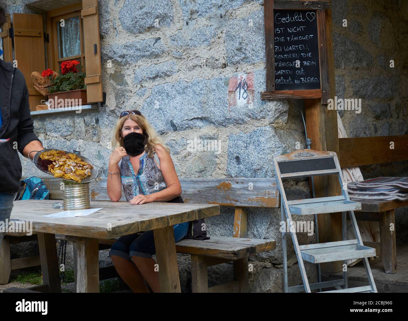 Frau mit Schutzmaske essen lokale Lebensmittel, Südtirol Stockfoto