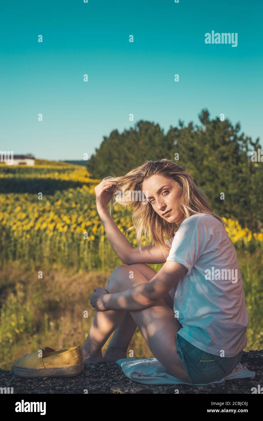 Junge Frau, die ihre Haare hält und in ländlicher Umgebung posiert Stockfoto