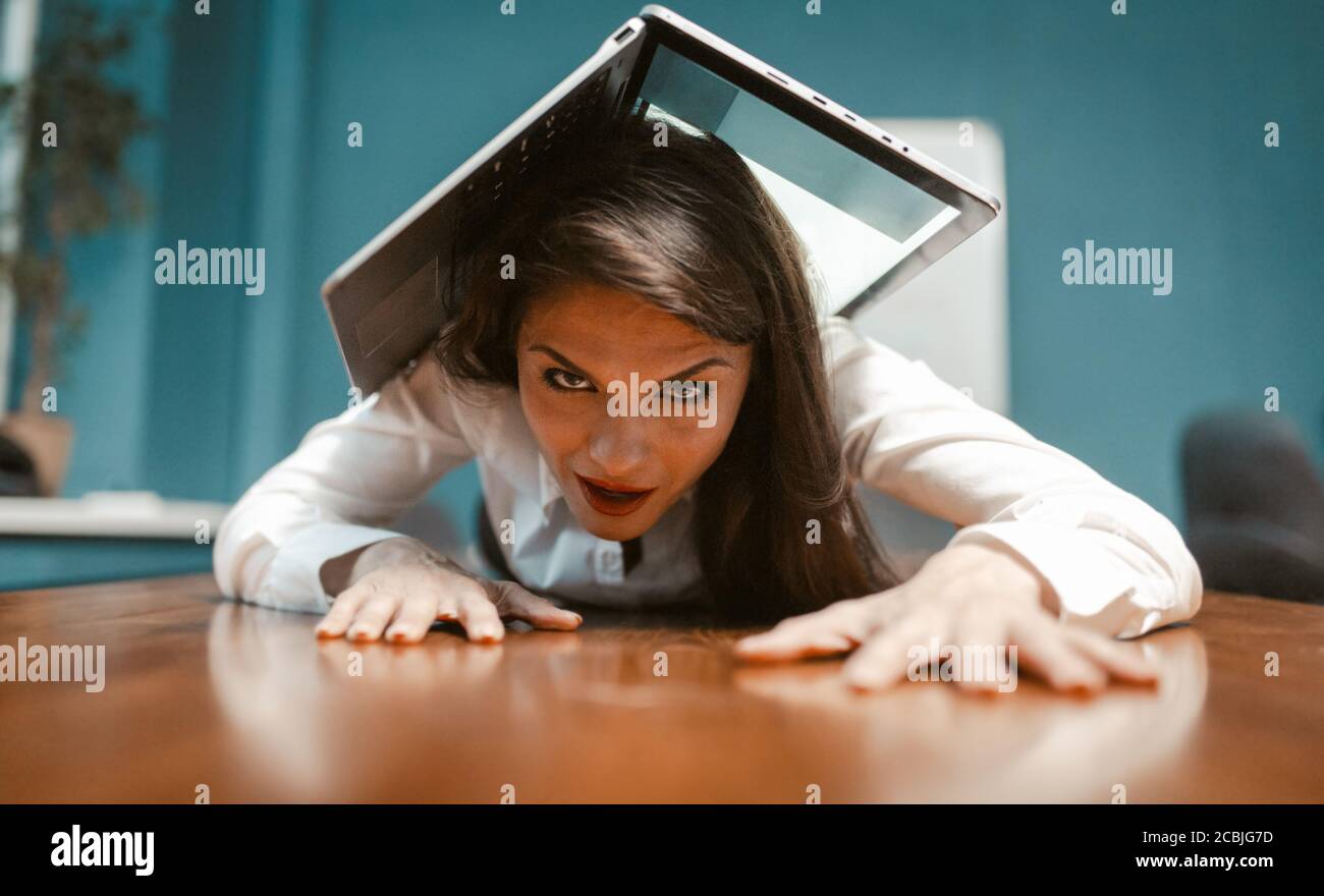 Verrückte Geschäftsfrau mit Laptop bedeckt, während sie auf dem Schreibtisch lag. Zeit, um in den Urlaub zu gehen. Konzept der Ermüdungsfestigkeit. Getöntes Bild Stockfoto
