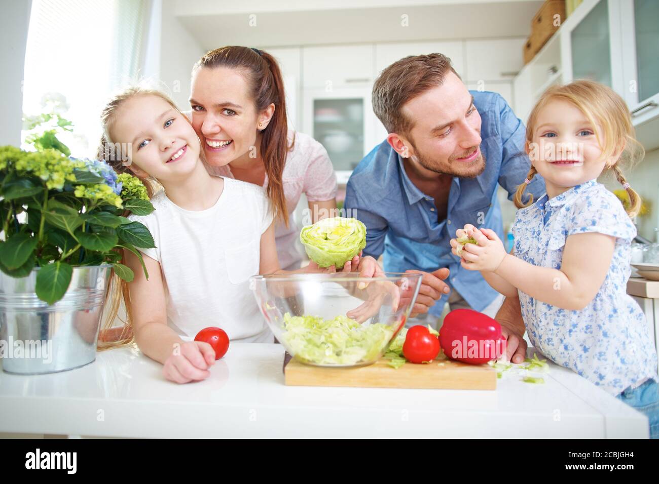 Glückliche Familie mit zwei Kindern macht frischen Salat in der Küche Stockfoto