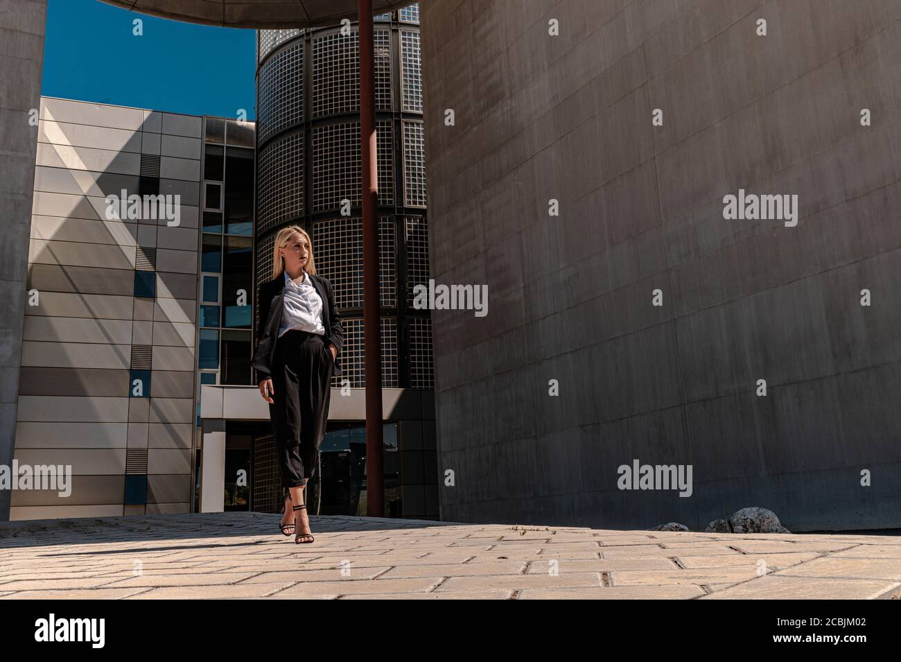 Eine junge blonde Geschäftsfrau in formeller Kleidung, die in der Nähe ist Das Gebäude Stockfoto
