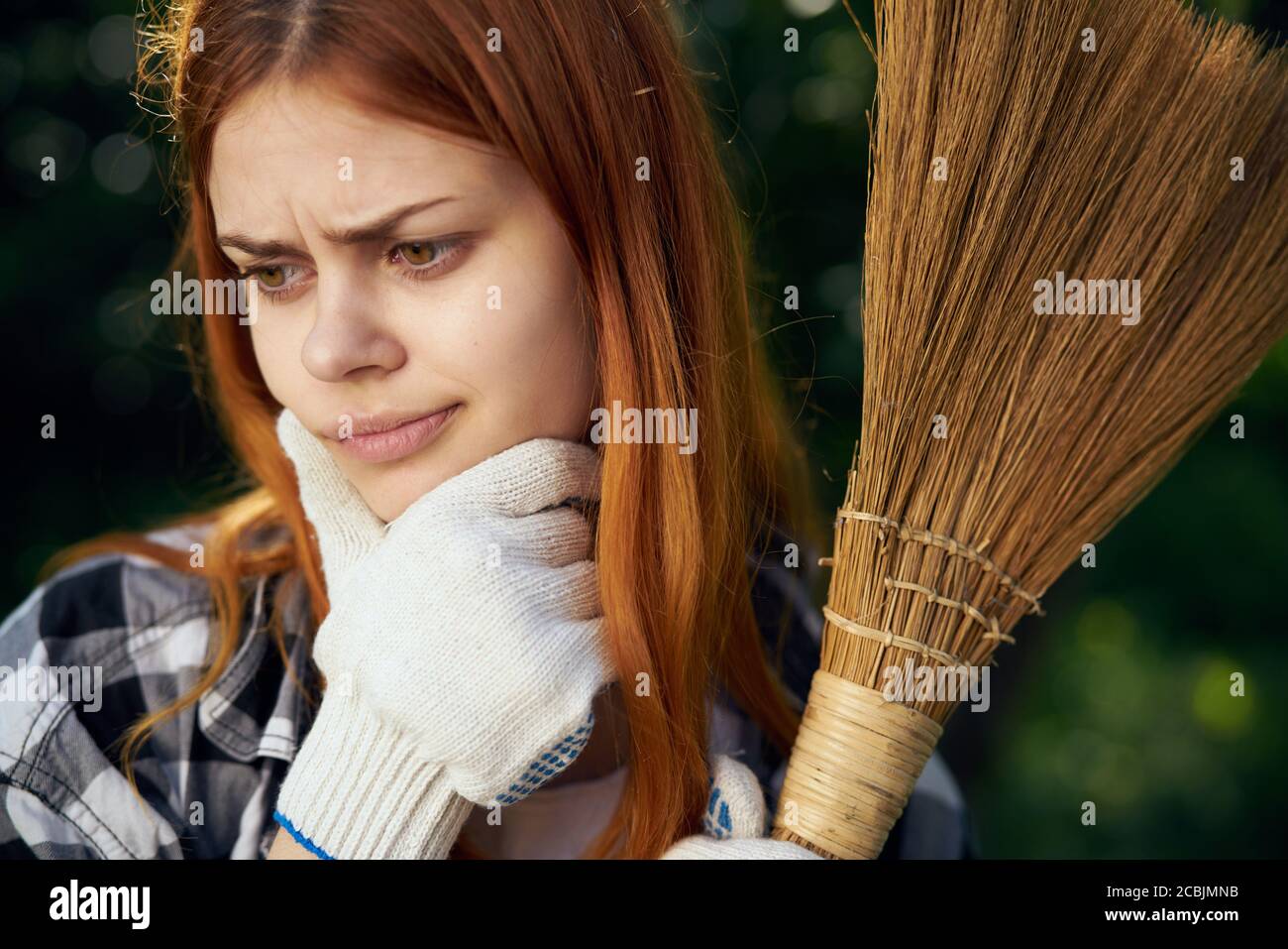 Frau mit Besen in den Händen Bauhandschuhe Reinigung des Gartens Frische Luft Stockfoto