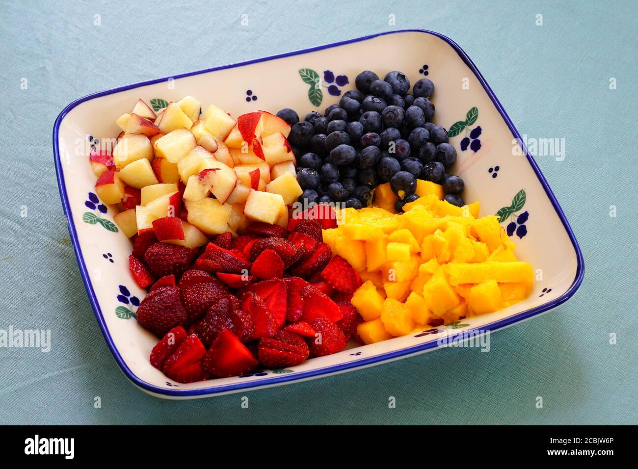 Ein gesunder Obstteller mit frischer Mango, Pfirsichen und Beeren Stockfoto