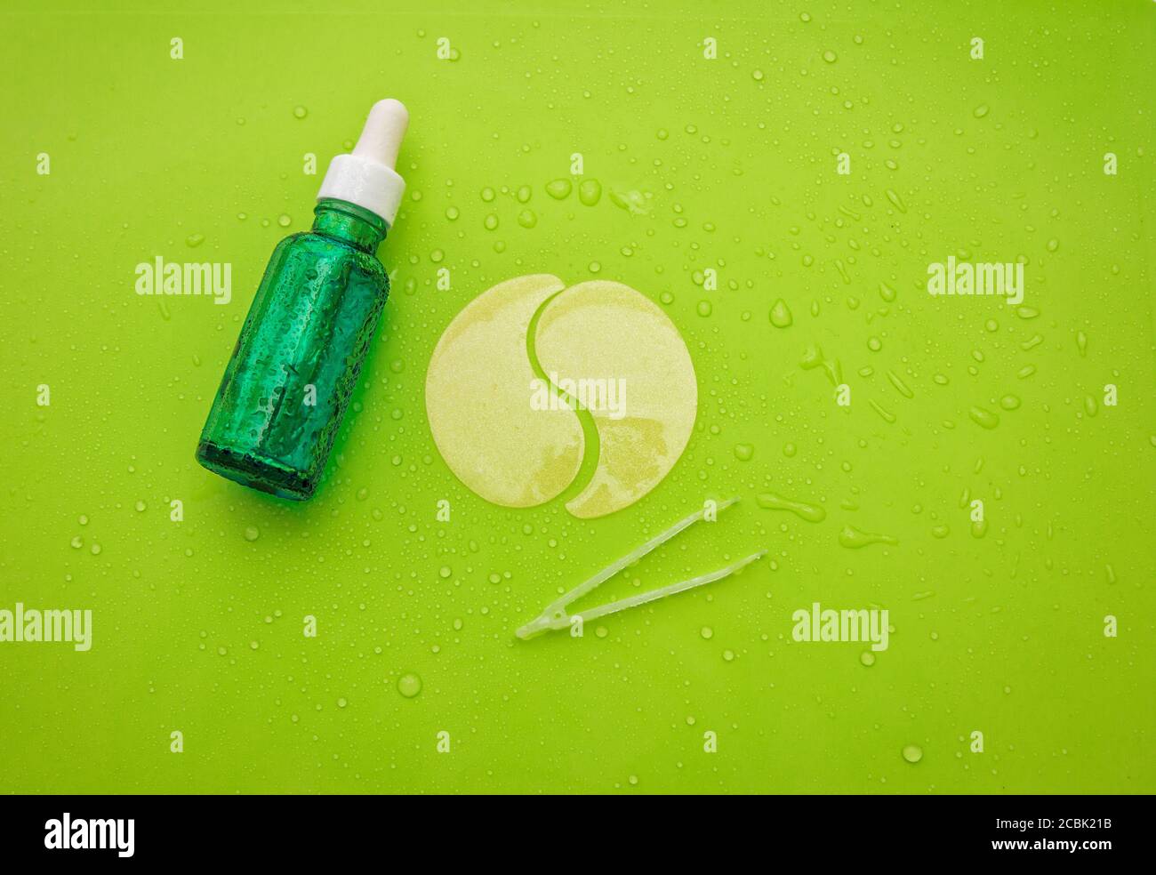 Hydrogel kosmetische Befeuchtung Kollagen Augenflecken und Gesicht Anti-Aging-Serum ina Flasche auf grünem Hintergrund mit Wassertropfen Stockfoto