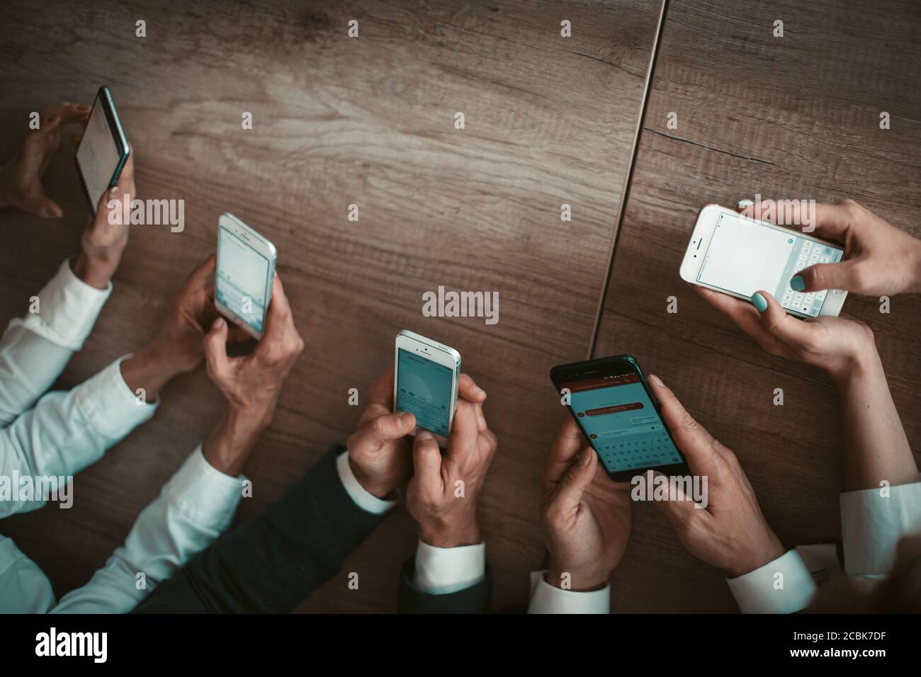 Gruppe von Büroangestellten, die auf Mobiltelefonen chatten, während sie Textanwendungen auf Smartphones verwenden. Mobile Business Meeting-Konzept. Nahaufnahme des Menschen Stockfoto