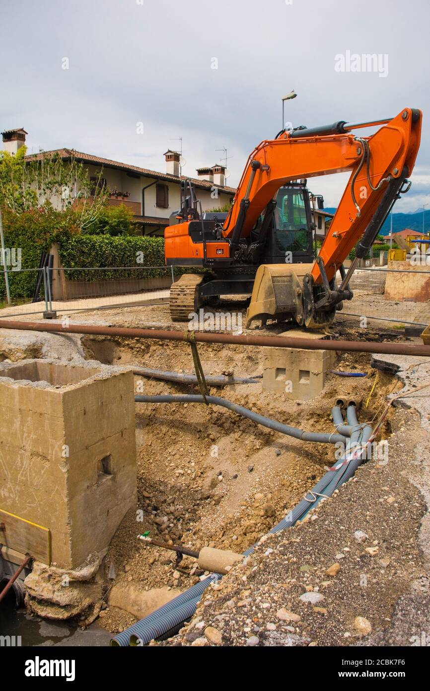 Ein Kanalbrunnen Graben und ein Raupenbagger mit einem Rotierende Hausplattform & durchgehende Raupenbahn auf einem Kanal Ersatzarbeitplatz im Nordosten Italiens Stockfoto