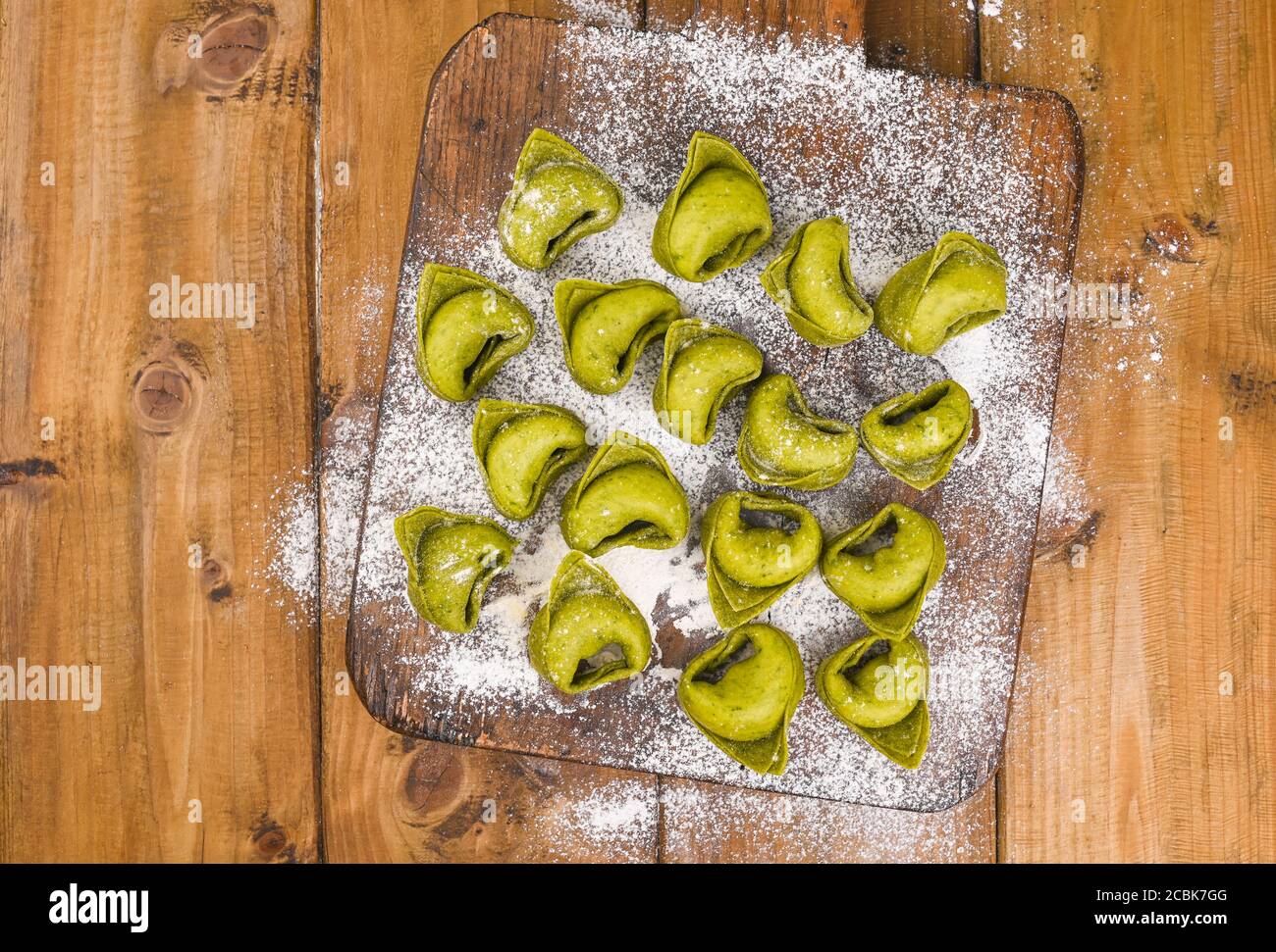 Tortellini e Tortelloni typische Gerichte emilia italien. Food Hintergrund mit hausgemachten rohen italienischen Tortelloni und Zutaten für grünes Pesto auf Holzhintergrund . Weitwinkelansicht. Speicherplatz kopieren. Stockfoto