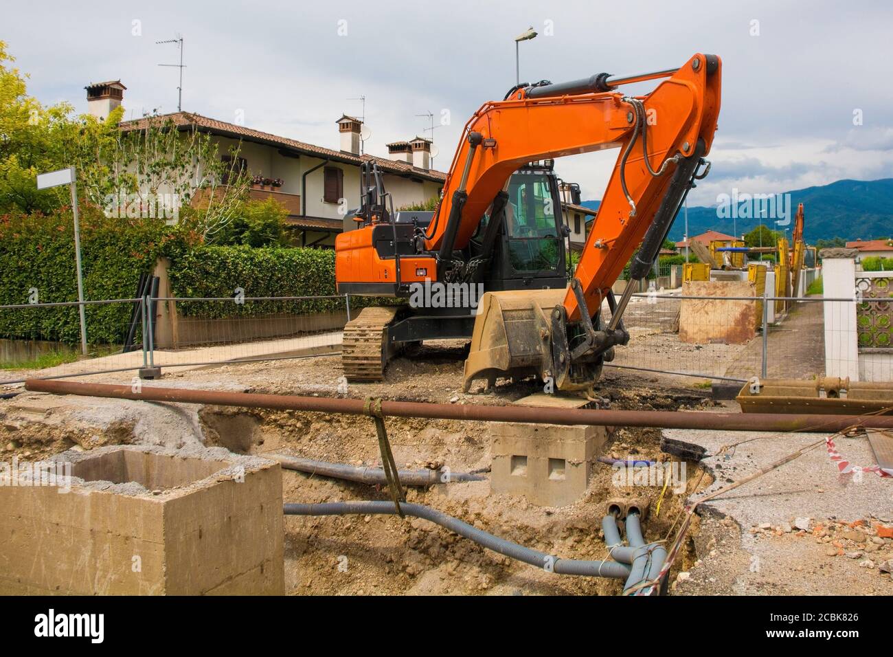 Ein Kanalbrunnen Graben und ein Raupenbagger mit einem Rotierende Hausplattform & durchgehende Raupenbahn auf einem Kanal Ersatzarbeitplatz im Nordosten Italiens Stockfoto