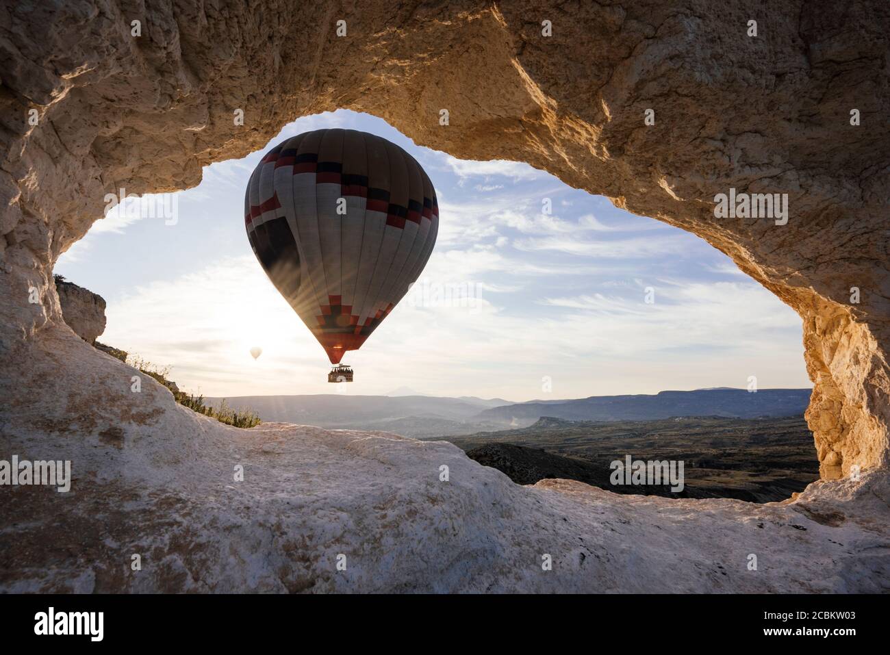 Heißluftballon umrahmt zwischen Felsformation bei Sonnenaufgang, Goreme Nationalpark, Kappadokien, Anatolien, Türkei Stockfoto