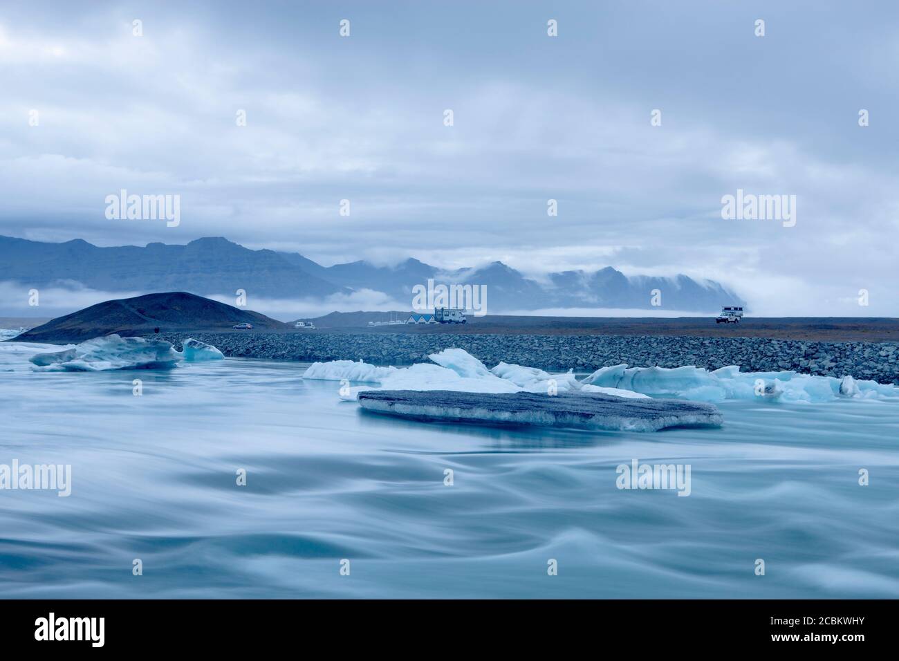 Bergkette und Eisberge, die auf der Gletscherlagune des Flusses Jokulsarlon, Island, schwimmen Stockfoto
