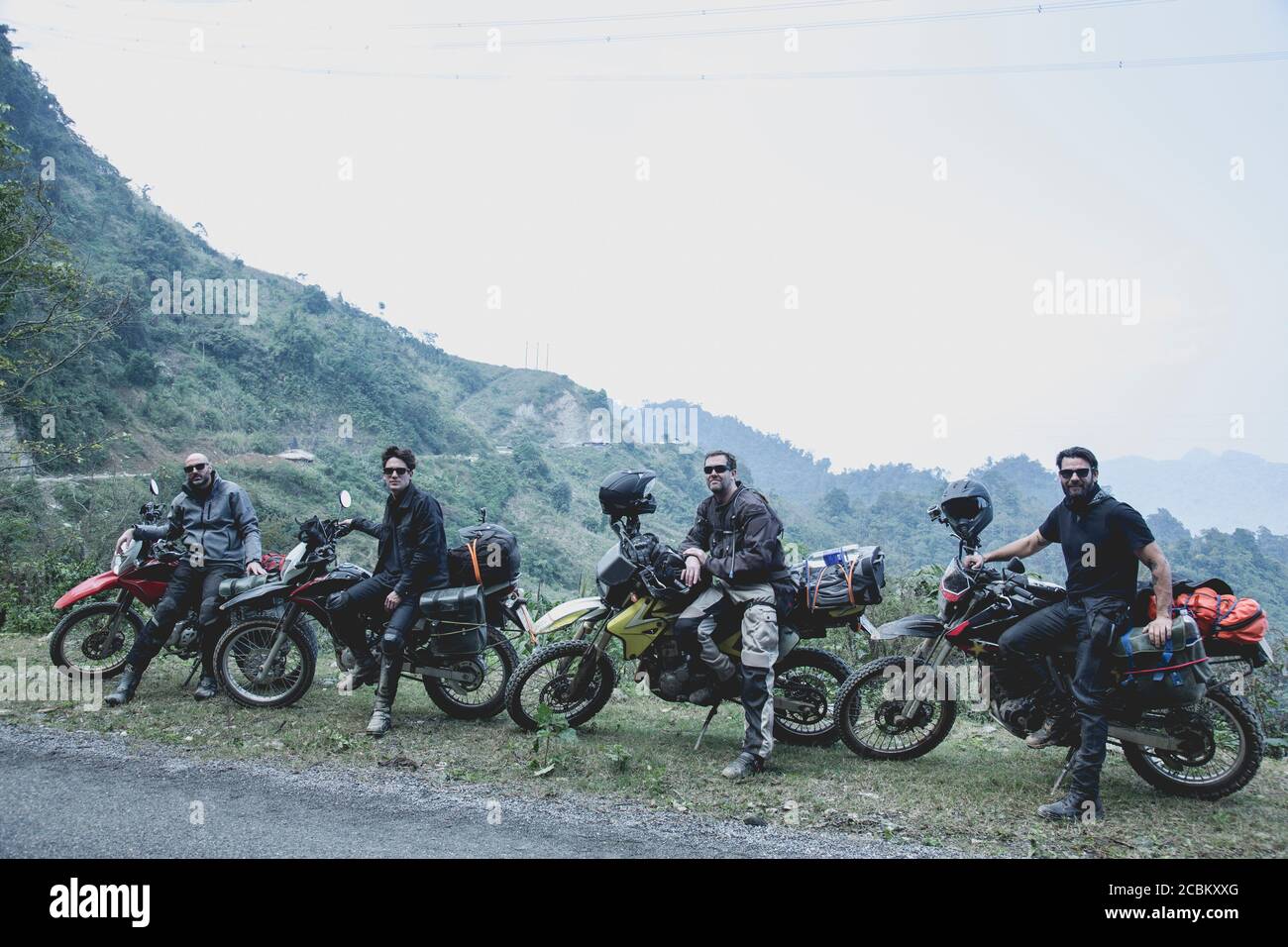 Vier Männer mit ihren Motorrädern in der ländlichen Landschaft, Vietnam Stockfoto