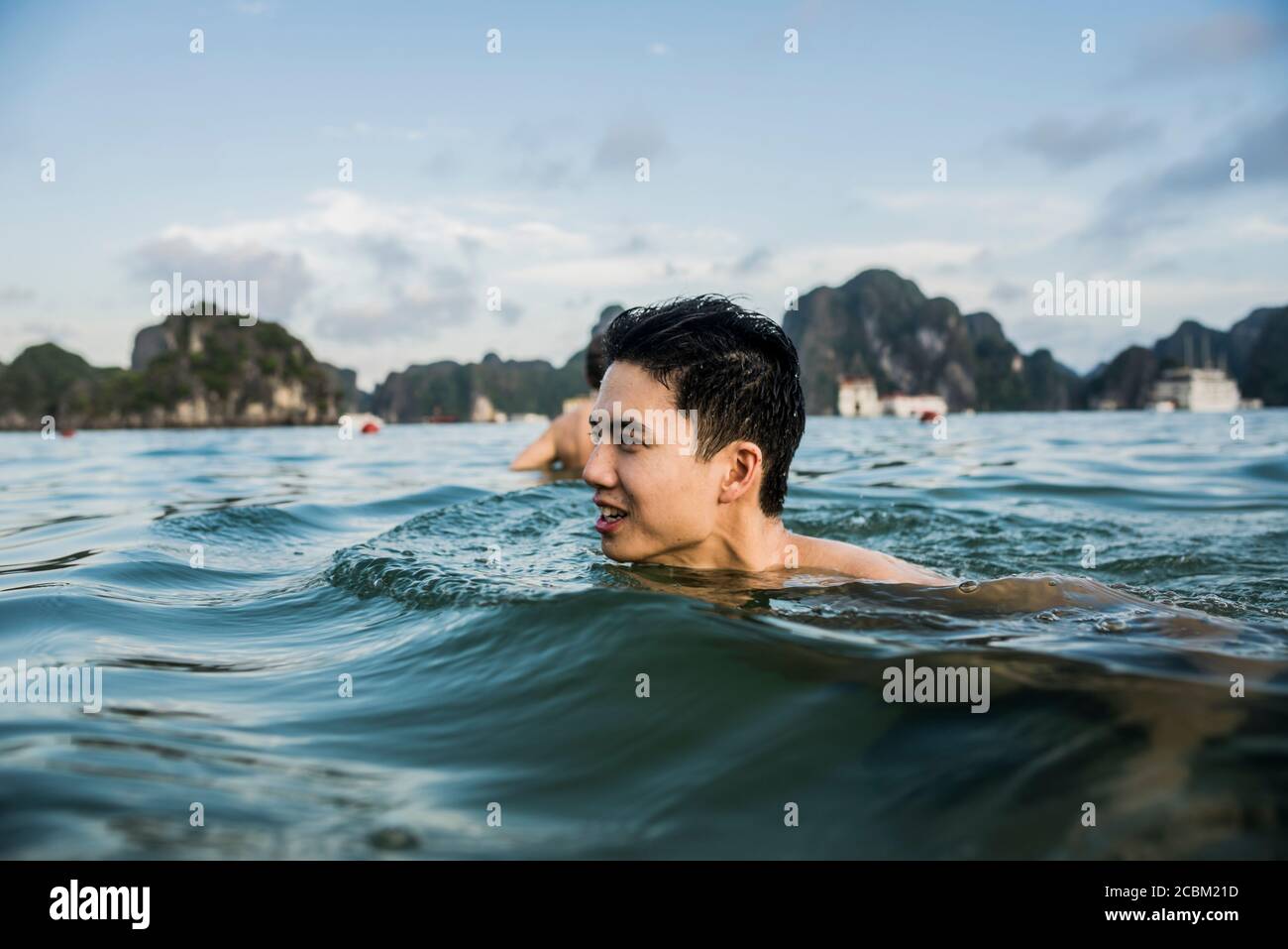 Mann schwimmt in den Gewässern von Ha Long Bay, Vietnam Stockfoto
