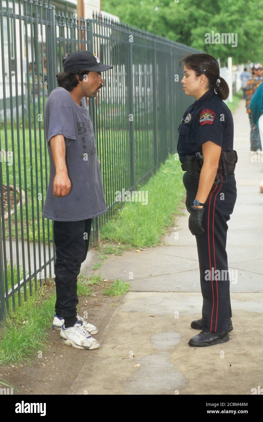 Austin, Texas, USA, 1996: Eine weibliche Hispanic-Beamtin spricht mit einem hispanischen Mann während ihrer Patrouille über den Nachbarschaftsschlag. Modellversion. ©Bob Daemmrich Stockfoto