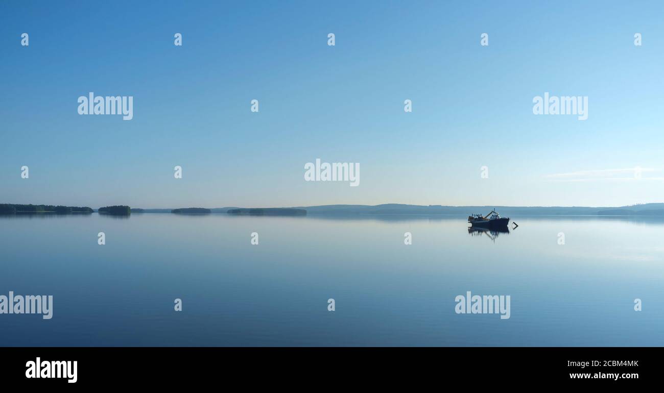 Ein kleiner verankerter Binnensee Fischtrawler am flachen ruhigen See Pohjois-Konnevesi am Sommerabend, Finnland Stockfoto