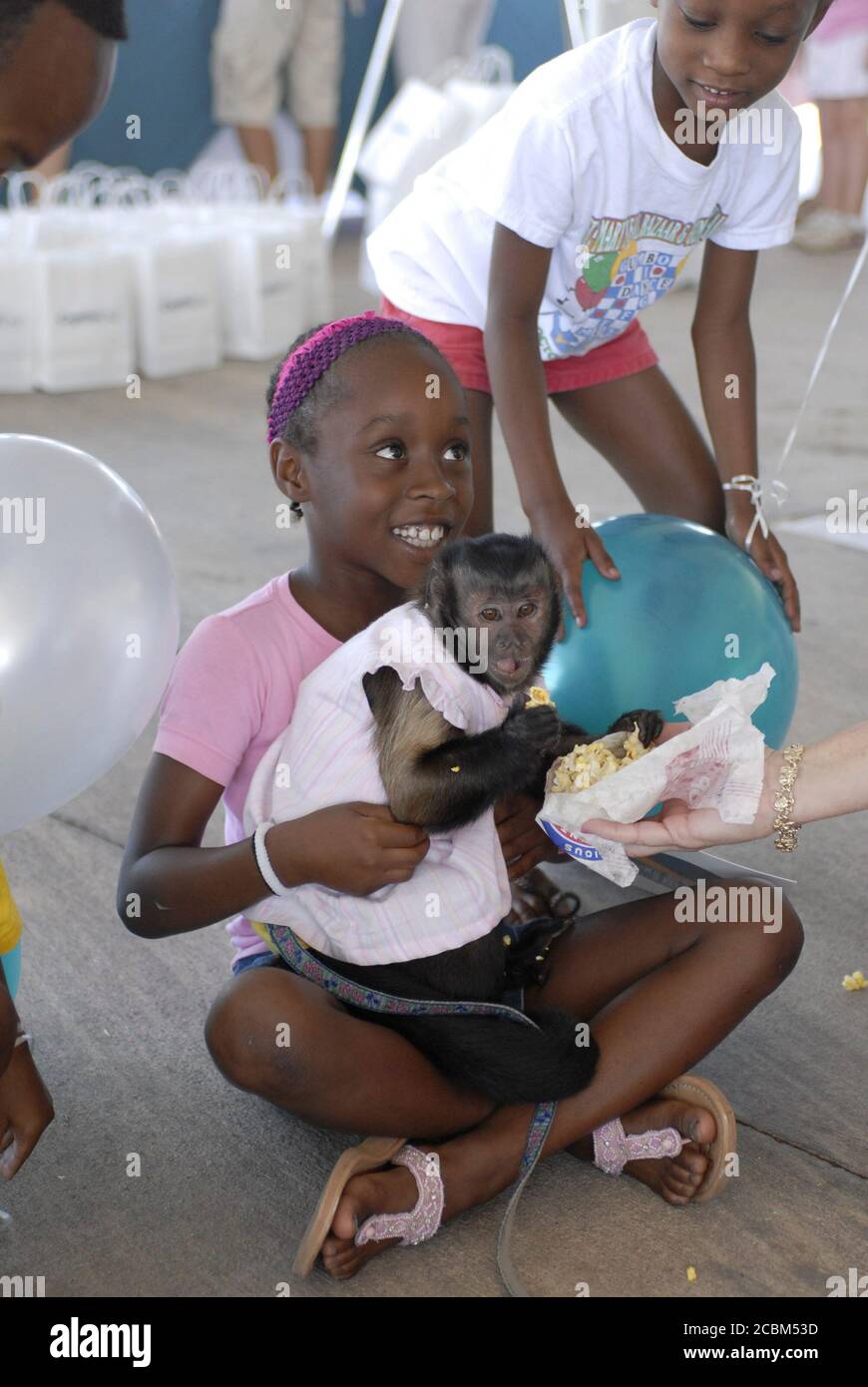 Georgetown, TX 5. August 2006: Kind spielt mit ausgebildeten Affen, die bei der Eröffnung einer Zweigstelle des Capital One-Bankzentrums nördlich von Austin in einem schnell wachsenden Vorstadtgebiet Unterhaltung boten. ©Bob Daemmrich Stockfoto