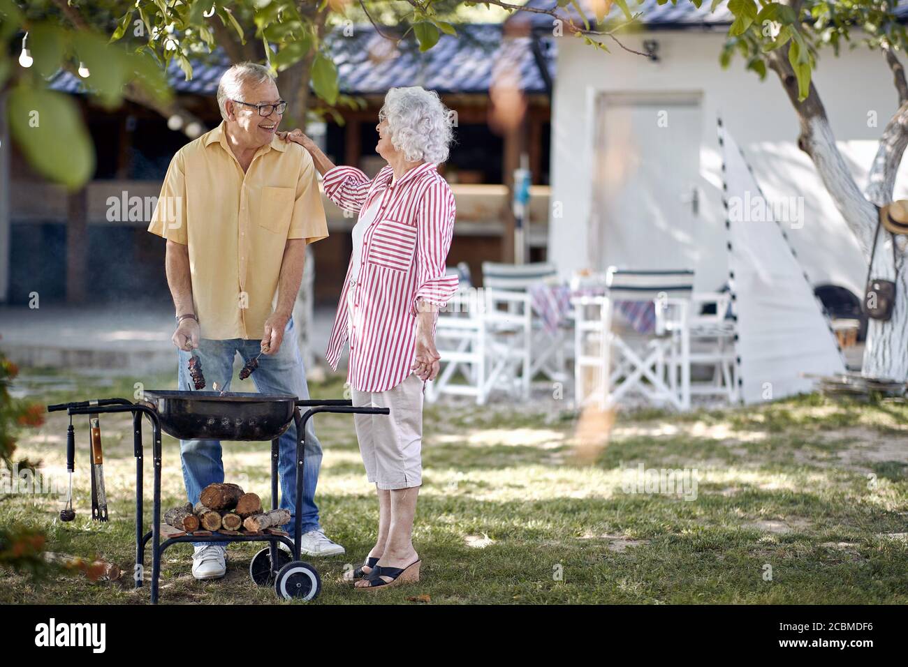 Glückliches Senior-Paar draußen Kochen auf EINEM Sommer Barbecue. Stockfoto