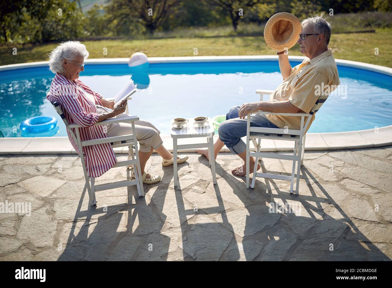 Ältere Mann und Frau genießen im Sommerurlaub in der Nähe von Schwimmbad zusammen. Stockfoto