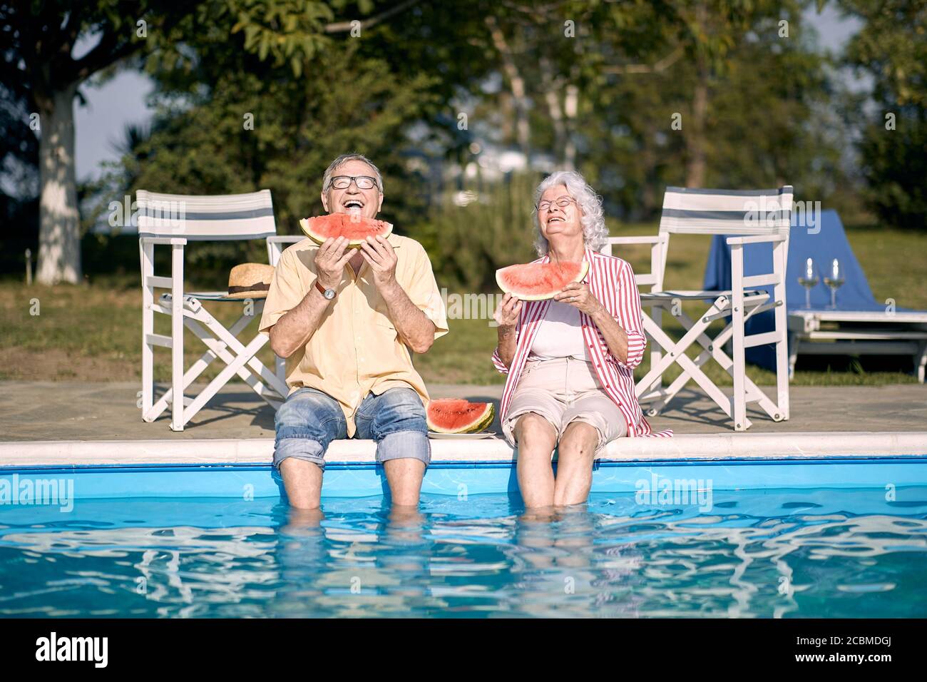 Ältere Paare essen Wassermelone am Pool.Happy Mann und Frau genießen im Sommerurlaub. Stockfoto