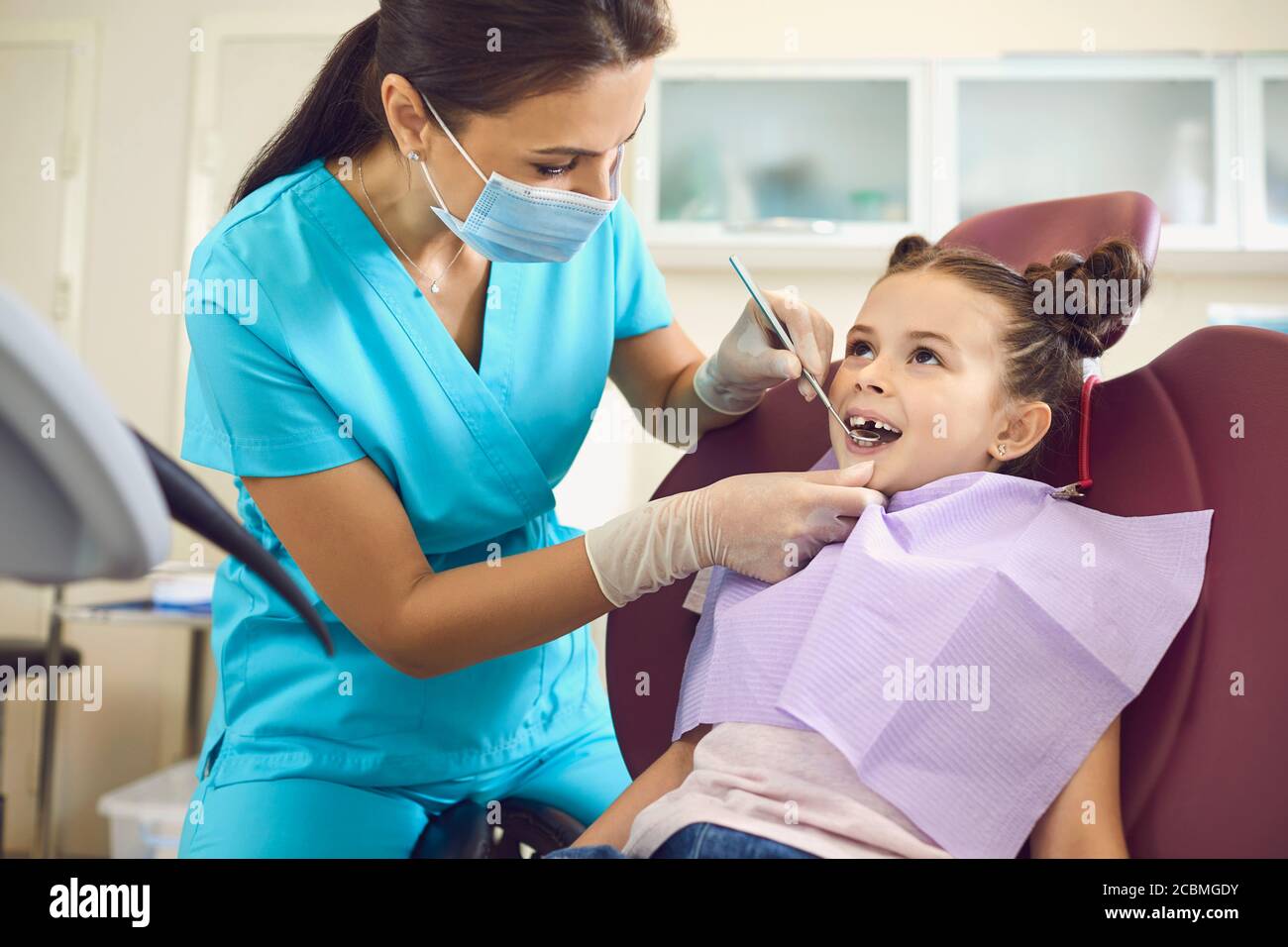 Kleines Mädchen bei einem pädiatrischen Zahnarzt mit Maske und Handschuhe Service Kinderzahnpflege in einer Zahnklinik. Stockfoto