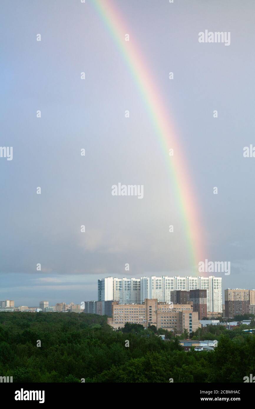 regenbogen in blau bewölkten Himmel über Hochhäusern in Sonniger Sommerabend Stockfoto