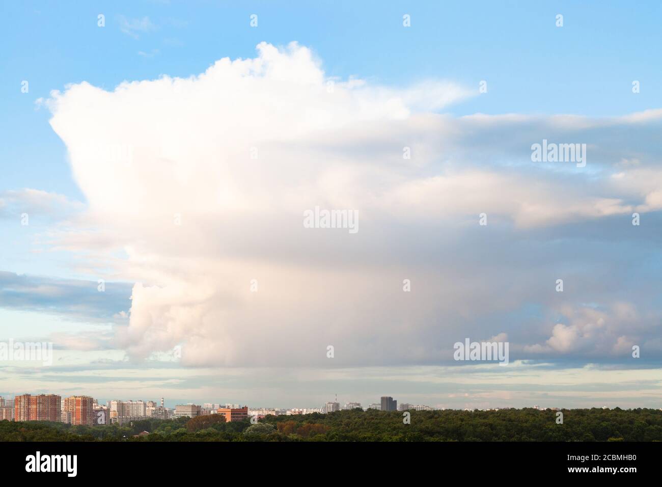 Große Wolke in blauen Himmel über Stadt und Stadtpark Im Sommerabend Stockfoto