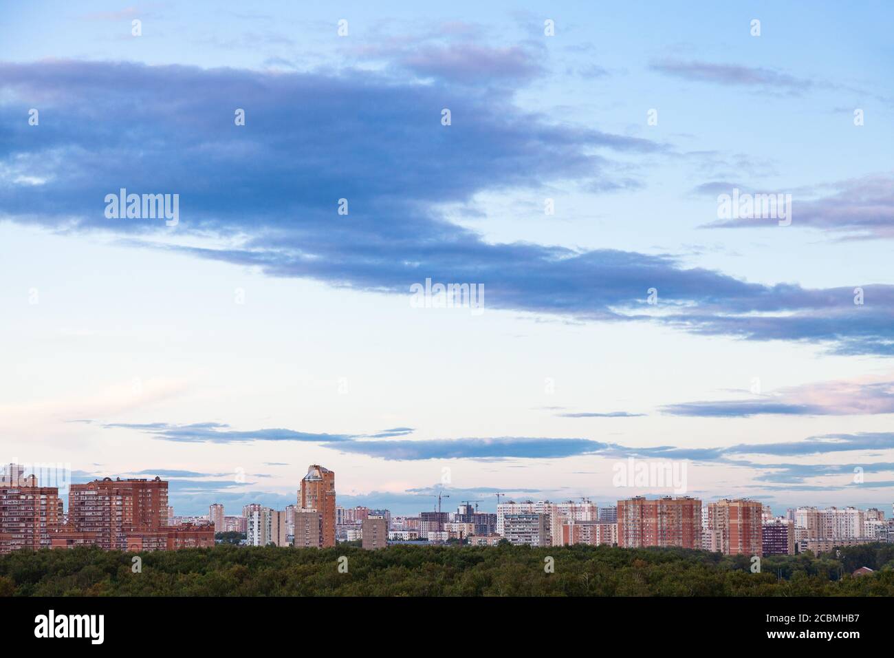 Blauer Himmel mit dunklen Wolken über Wohnhäusern in der Stadt Im Sommer Abenddämmerung Stockfoto