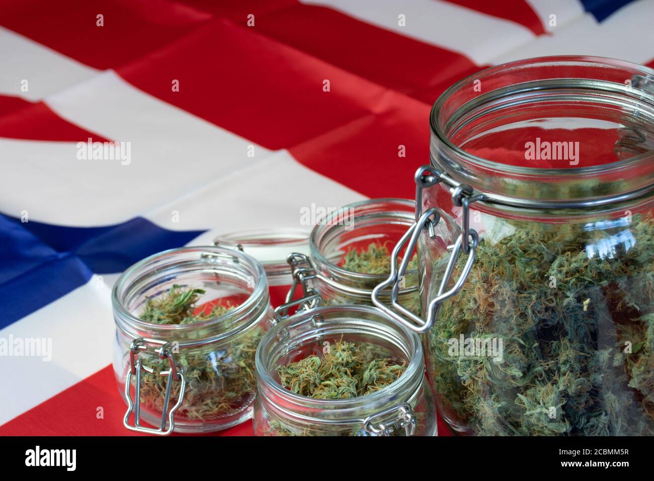 Offene Gläser mit Marihuana-Knospen auf dem Hintergrund mit der britischen Nationalflagge. Vereinigtes Königreich und Cannabisgeschäft Stockfoto