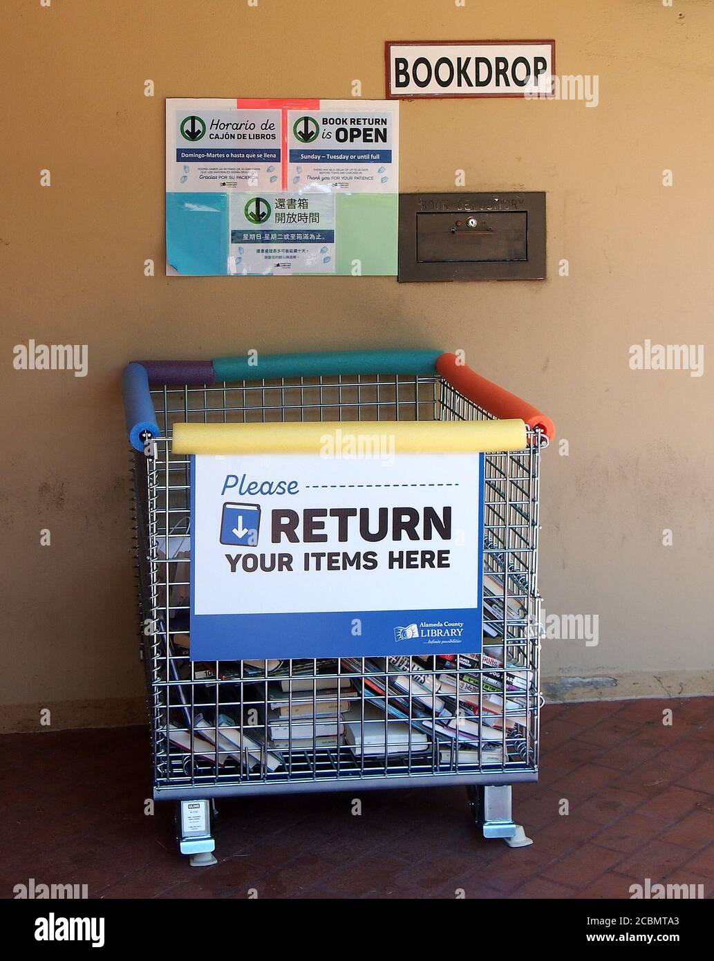 Bücher und Videos von außen bringen den Papierkorb vor der Alameda County Library in Union City zurück, während während der Pandemie, Kalifornien, keine Kontaktabnahmezeiten bestehen Stockfoto