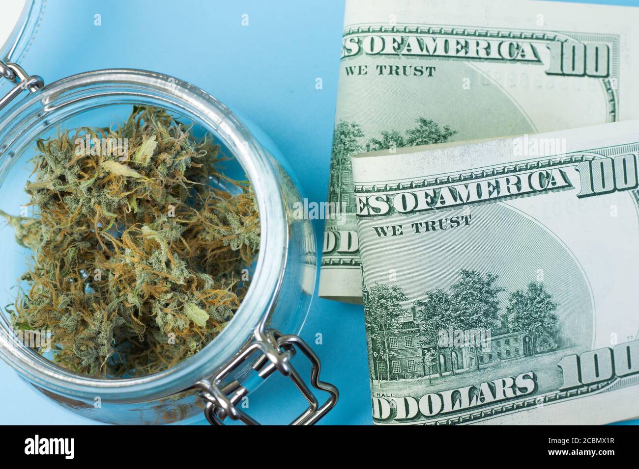 Cannabis THC Geschäftskonzept. Marihuana Knospen und Geld Dollar Banknoten Draufsicht. Unkrautinvestitionen Stockfoto