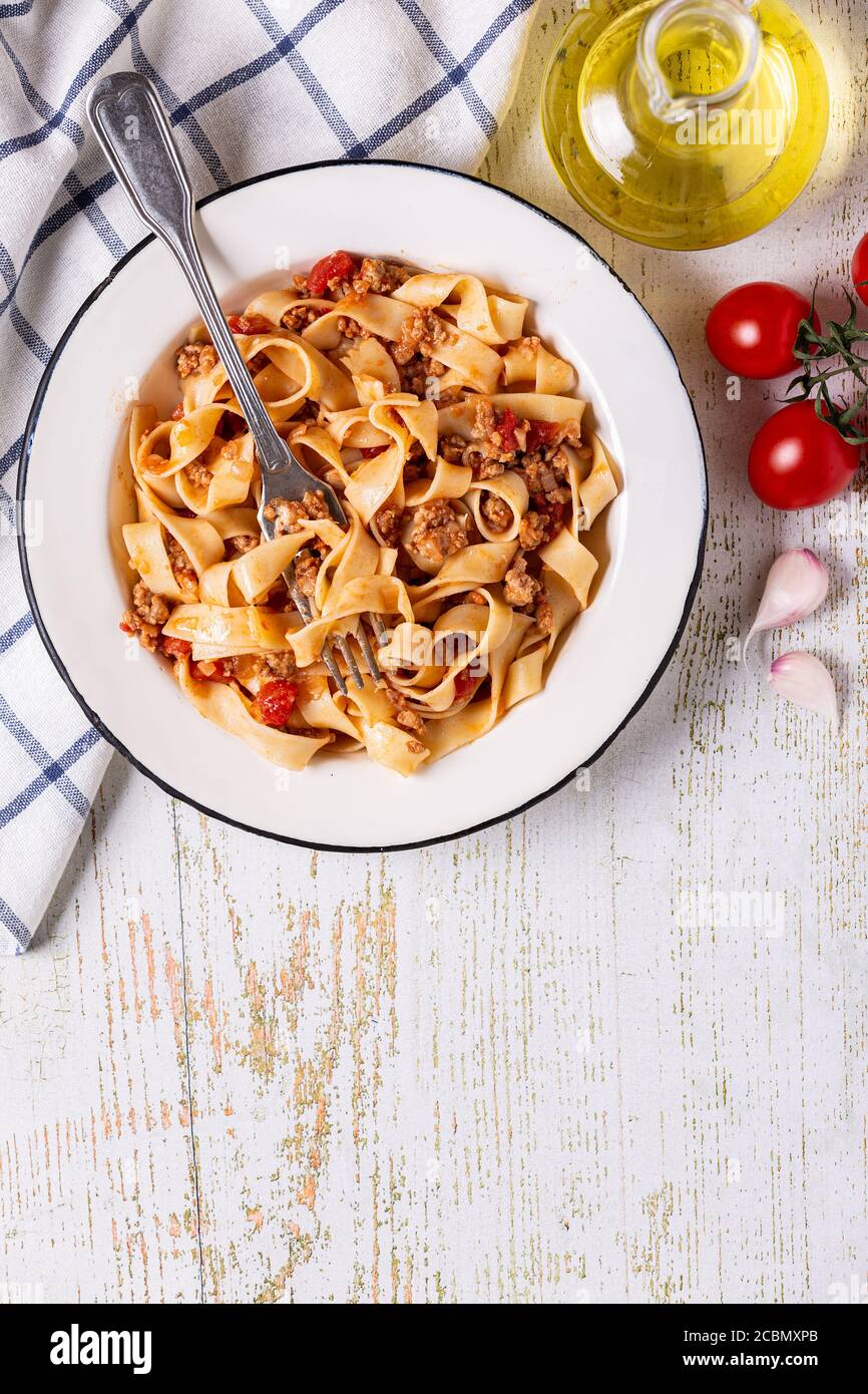 Traditionelle italienische Pasta Bolognese auf einem weißen Teller auf einem hölzernen Hintergrund, Draufsicht. Stockfoto