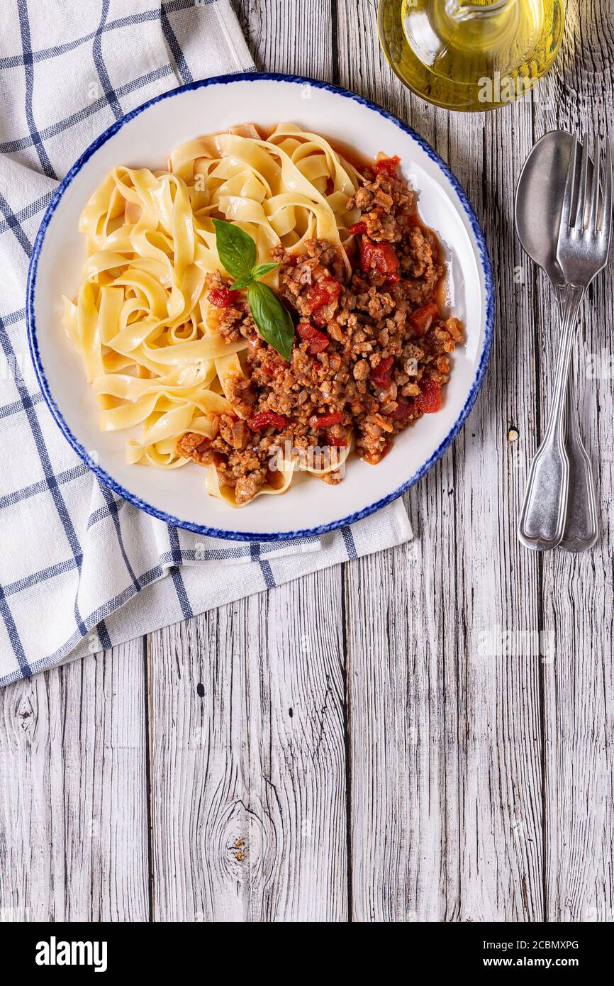 Traditionelle italienische Pasta Bolognese auf einem weißen Teller auf einem hölzernen Hintergrund, Draufsicht. Stockfoto