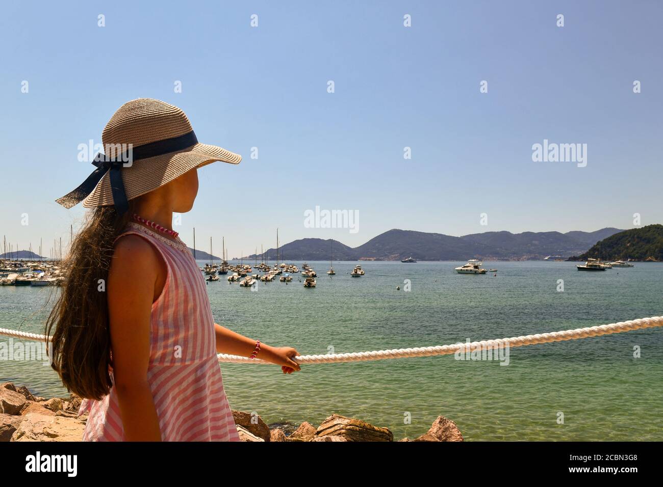 Porträt eines langhaarigen kleinen Mädchens (9-10 J.o.), das den Blick auf den Golf der Dichter mit dem Vorgebirge von Porto Venere, Lerici, La Spezia, Italien bewundert Stockfoto