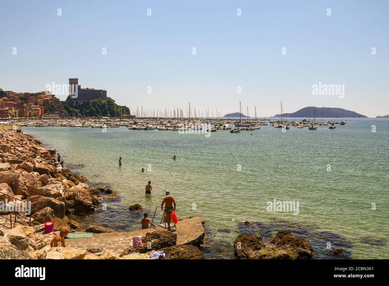 Blick auf den Golf der Dichter mit Menschen, die sich an der Küste abkühlen, den Hafen und das Fischerdorf mit der Burg, Lerici, La Spezia, Lig Stockfoto