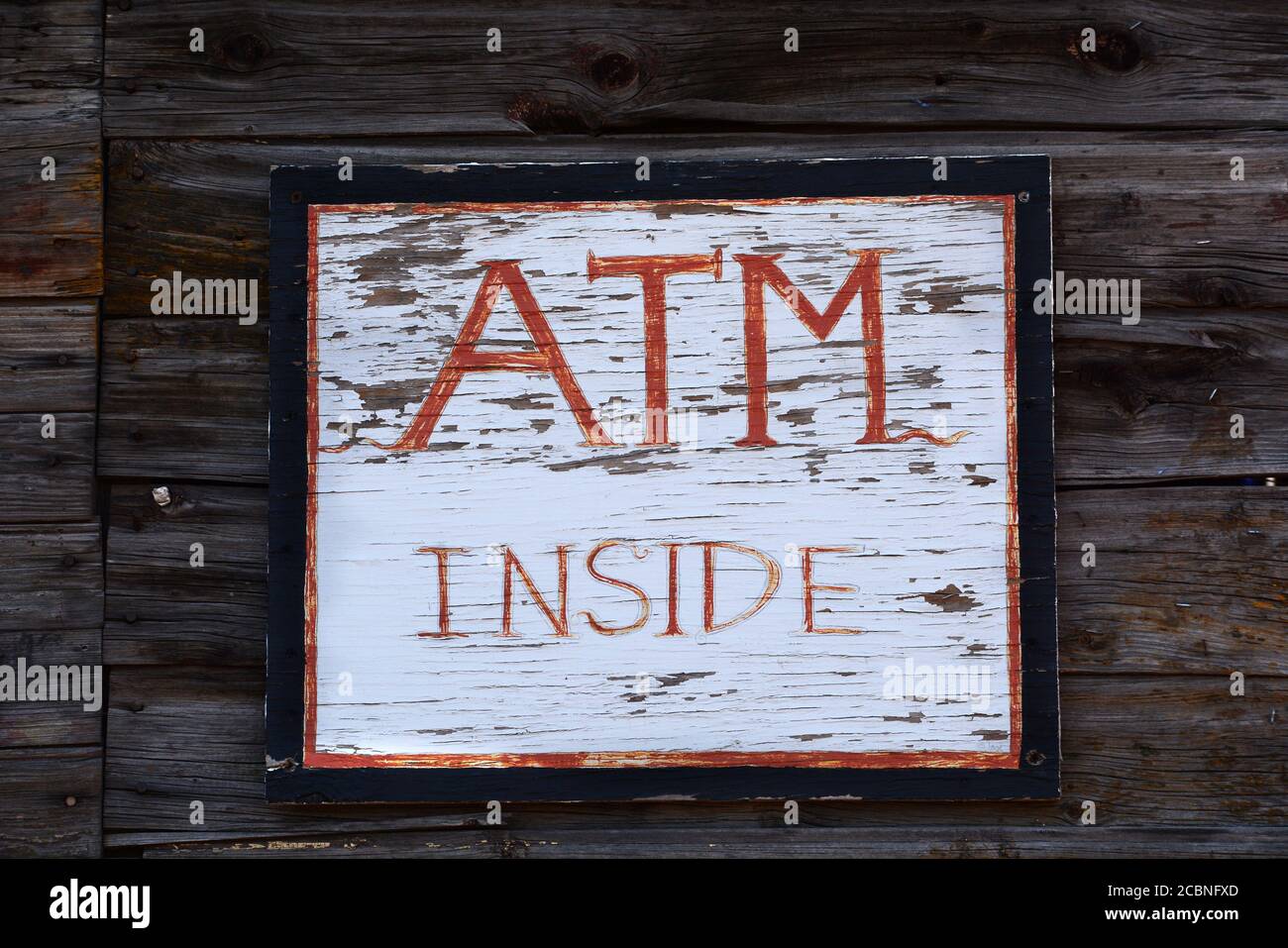 Ein handgefertigtes Schild weist Kunden darauf hin, dass sich im Laden ein Geldautomat befindet. Stockfoto
