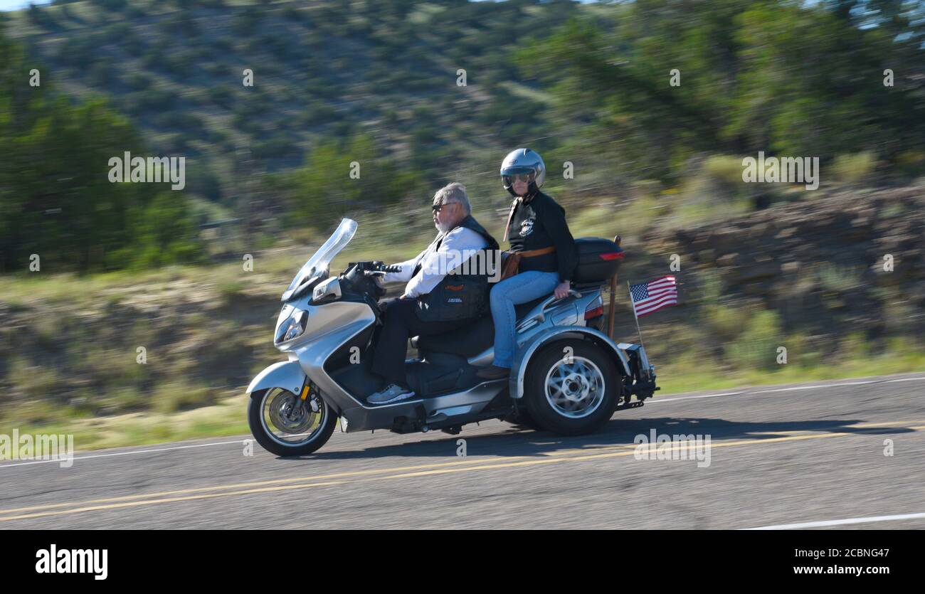 Ein Seniorenpaar fährt mit seinem Harley-Davidson Motorrad auf einer Straße im ländlichen Madrid, New Mexico USA Stockfoto